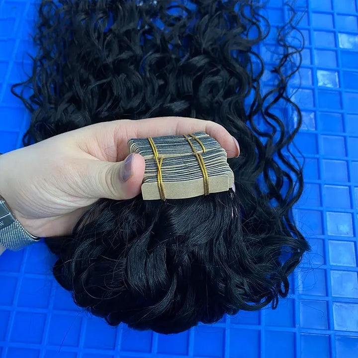 Water Wave tape-in extensions: Close-up of grouped tape tabs and wavy hair